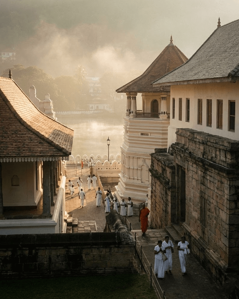 Morning mist surrounding the Temple of the Sacred Tooth Relic (Sri Dalada Maligawa) in Kandy, Sri Lanka with locals in white clothes.